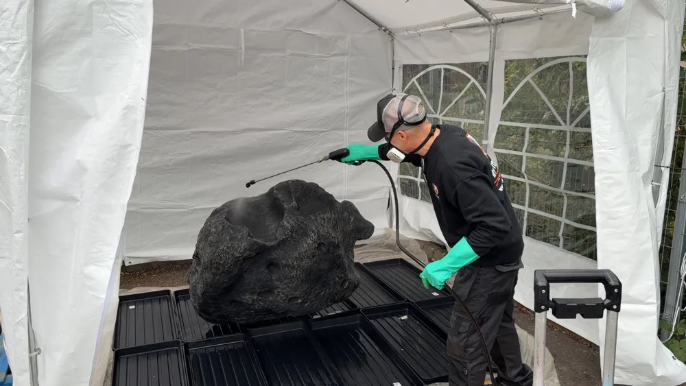 Fire Proofing Ltd technician spraying a large grey polystyrene rock