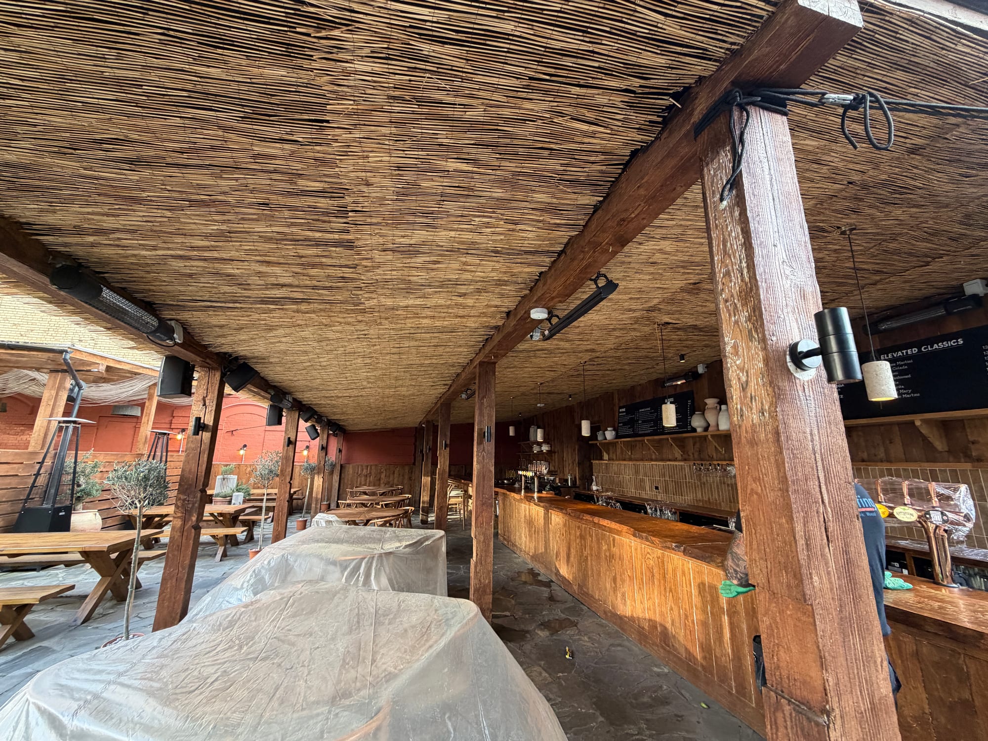 Large natural reed ceiling installation above a hospitality area prepared for on-site work